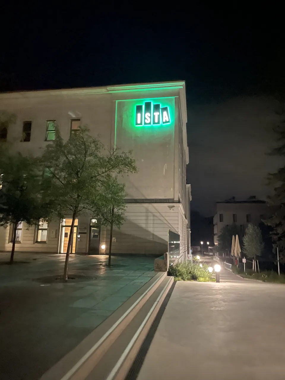 The illuminated ISTA sign on a campus building at night