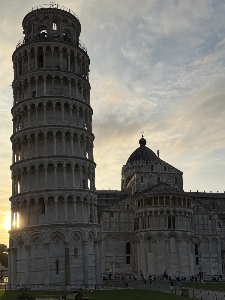 The Leaning Tower of Pisa beside the cathedral, with sunlight coming through the tower’s lower arches