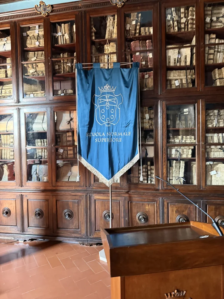 Wooden bookcases and a blue Scuola Normale Superiore banner