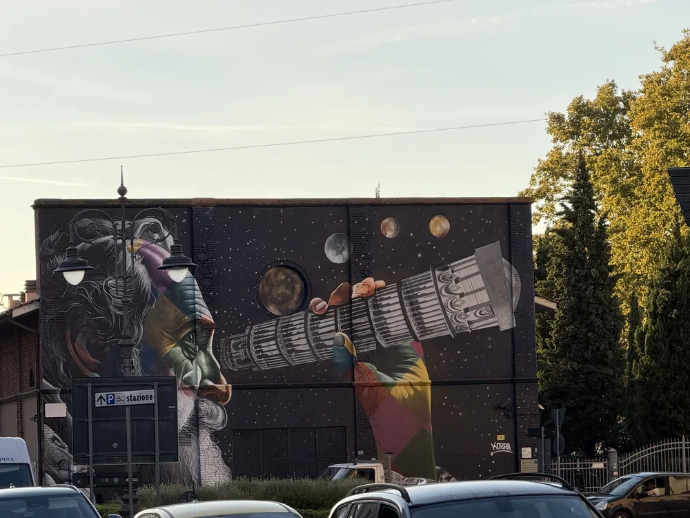 A Pisa street mural showing Galileo looking through a telescope shaped like the Leaning Tower