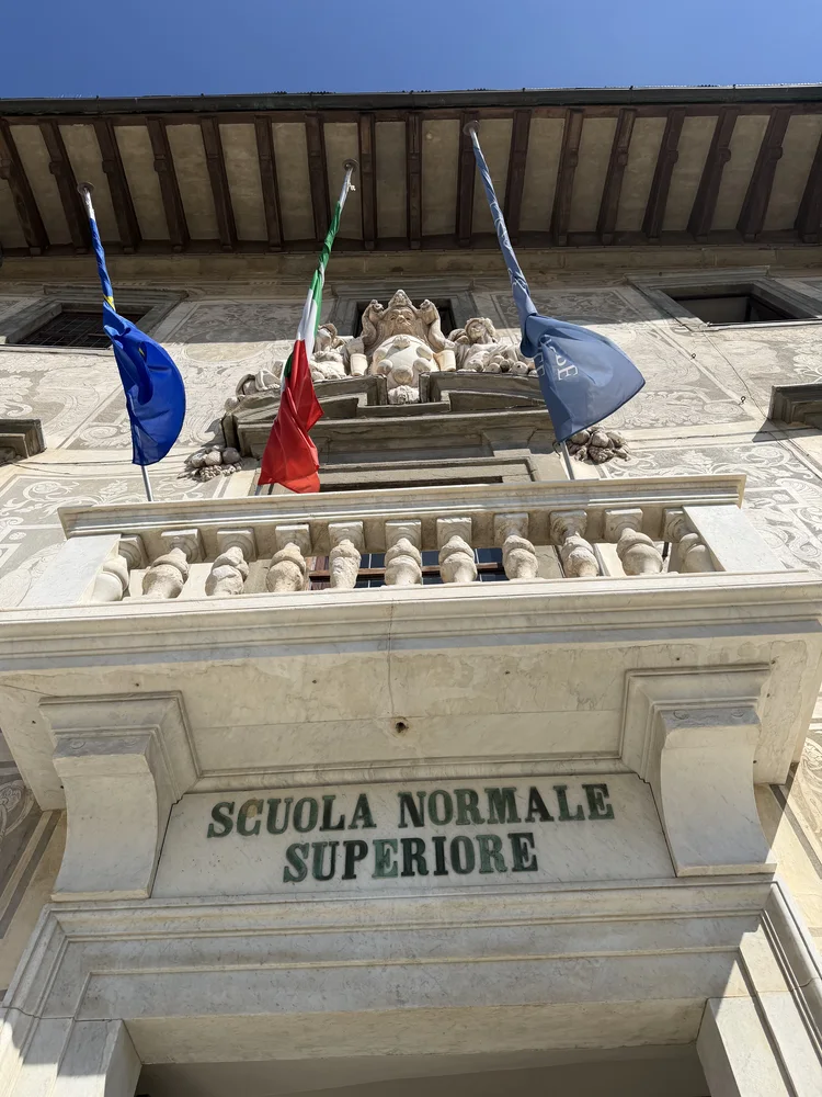 The Scuola Normale Superiore entrance, balcony and flags viewed from below